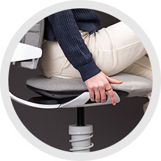 Person sitzt auf dem Aeris 3Dee und stellt über den Taster unter dem Sitzträger die passende Sitzhöhe ein.