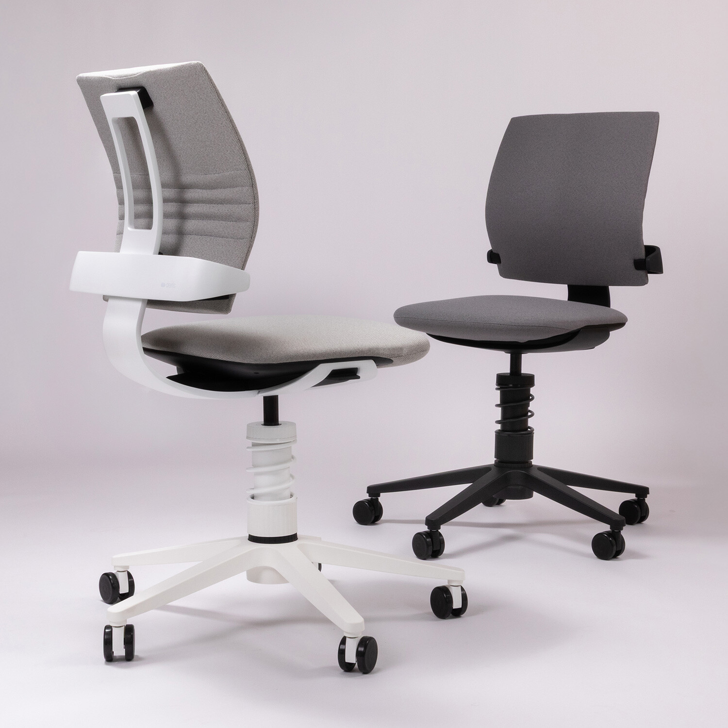 Zwei Bürostühle Aeris 3Dee vor grauem Hintergrund, links mit weißem Gestell und rechts mit schwarzem Gestell.
