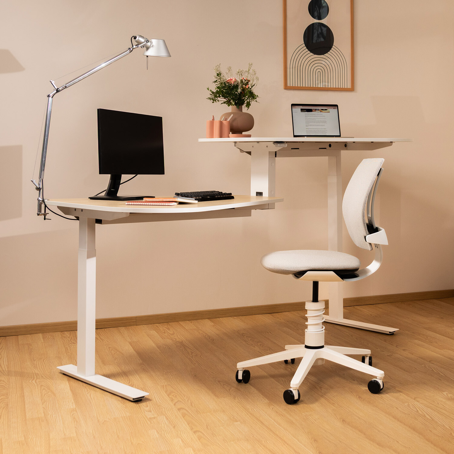 Aeris 3Dee mit weißem Gestell in modernem Raum mit hellem Parkettboden, positioniert vor einem Sitz-Steh-Schreibtisch.